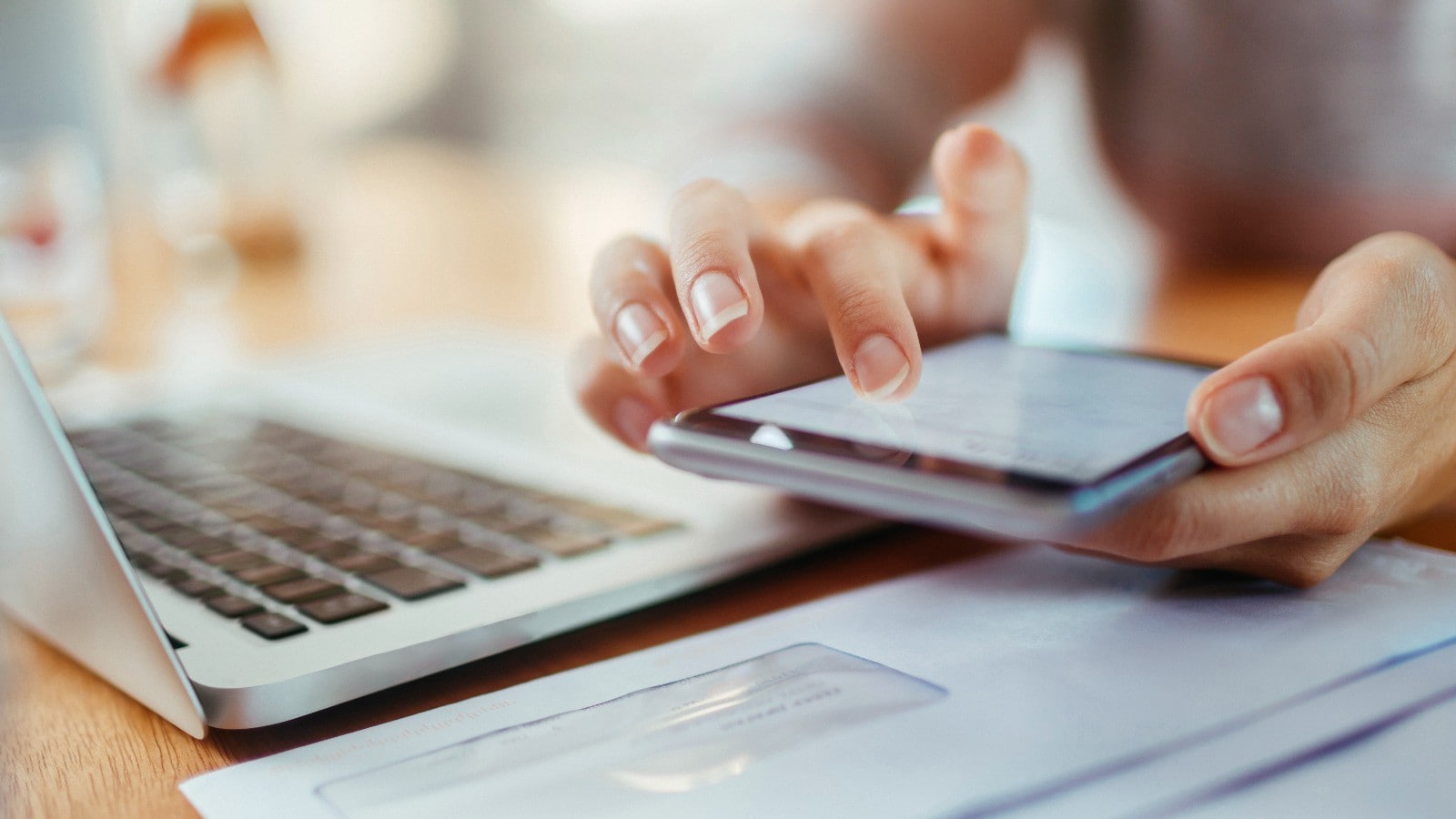 Frau mit Handy am Laptop