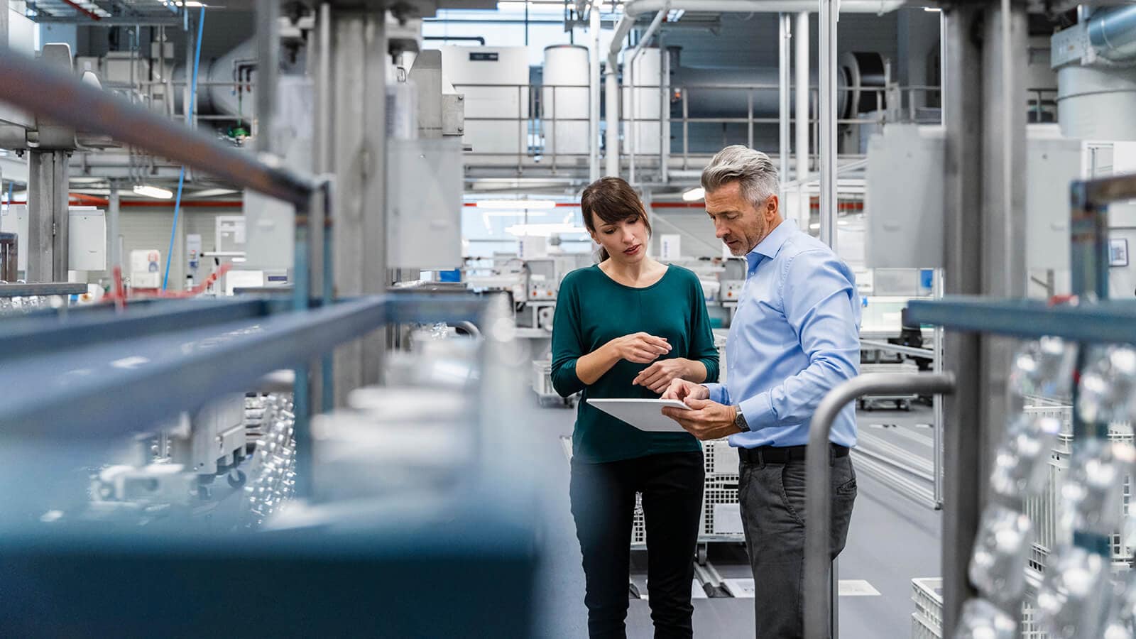Businesswoman discussing over tablet PC with coworker at factory