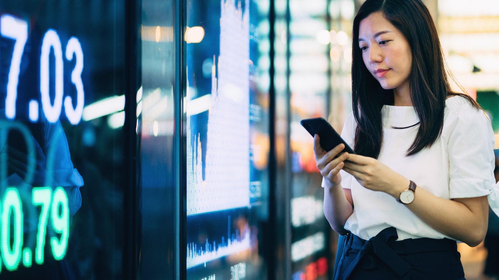 Woman checks trading data on smartphone