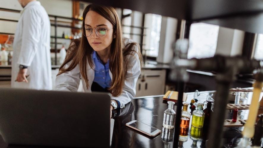 Chemist using computer in chemical laboratory