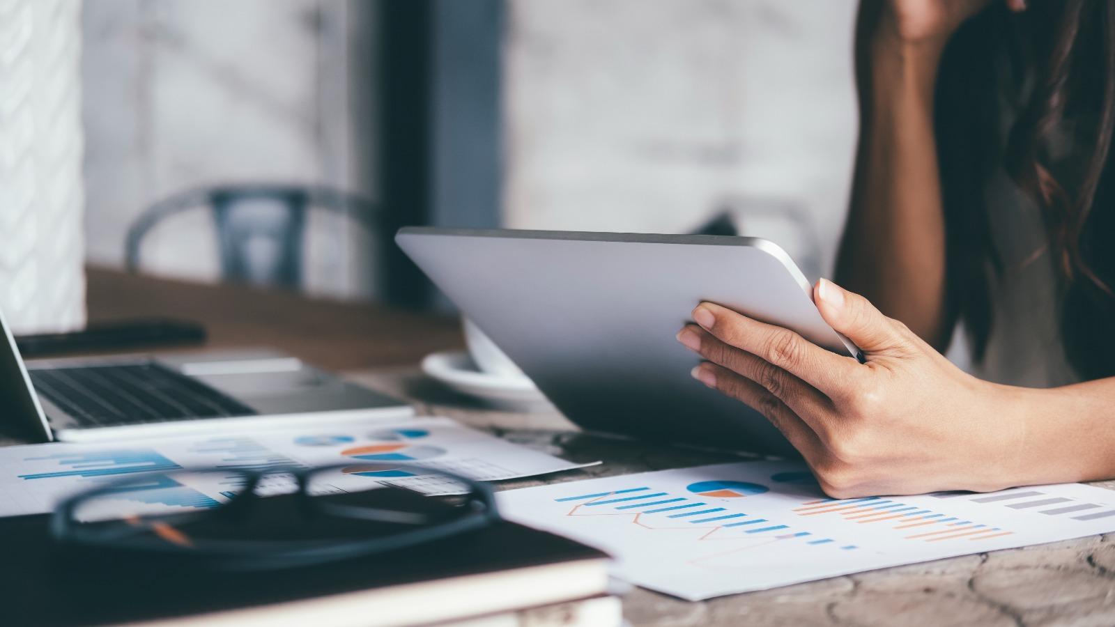 Hände halten Tablet am Schreibtisch