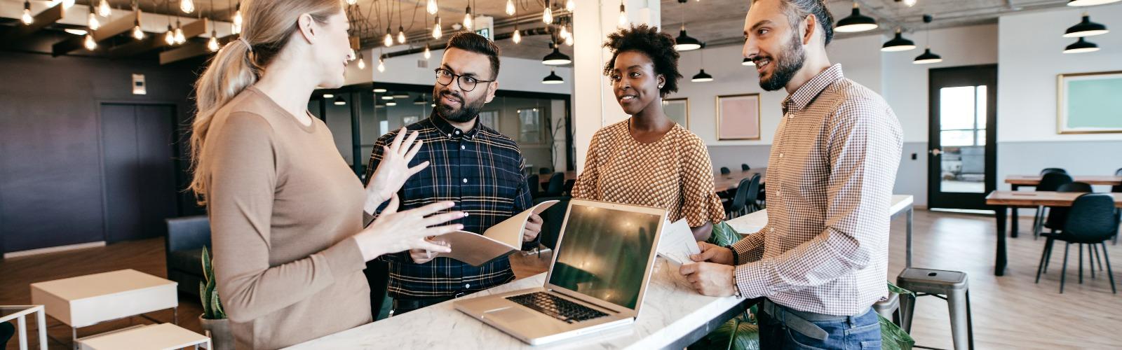 Frau mit Laptop erklärt Kollegen etwas