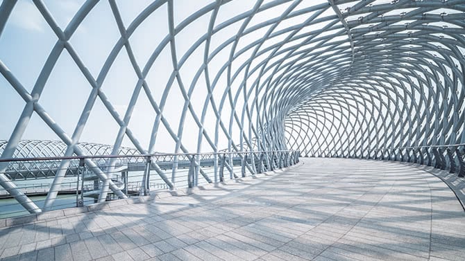 Futuristic pedestrian footbridge against sky.
