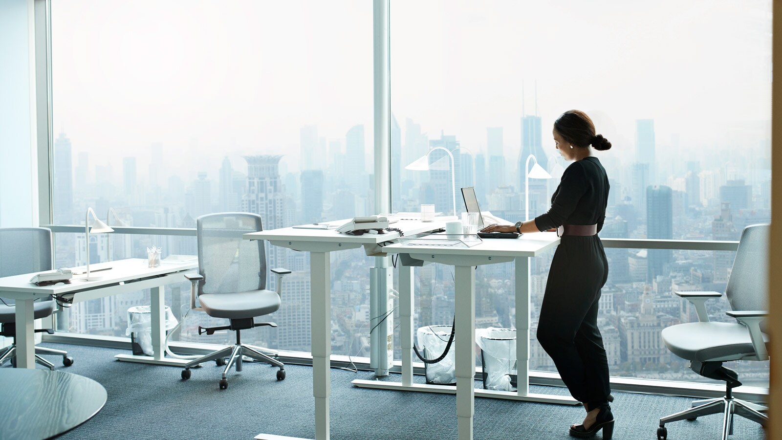 Geschäftsfrau vor Computer mit Skyline im Hintergrund