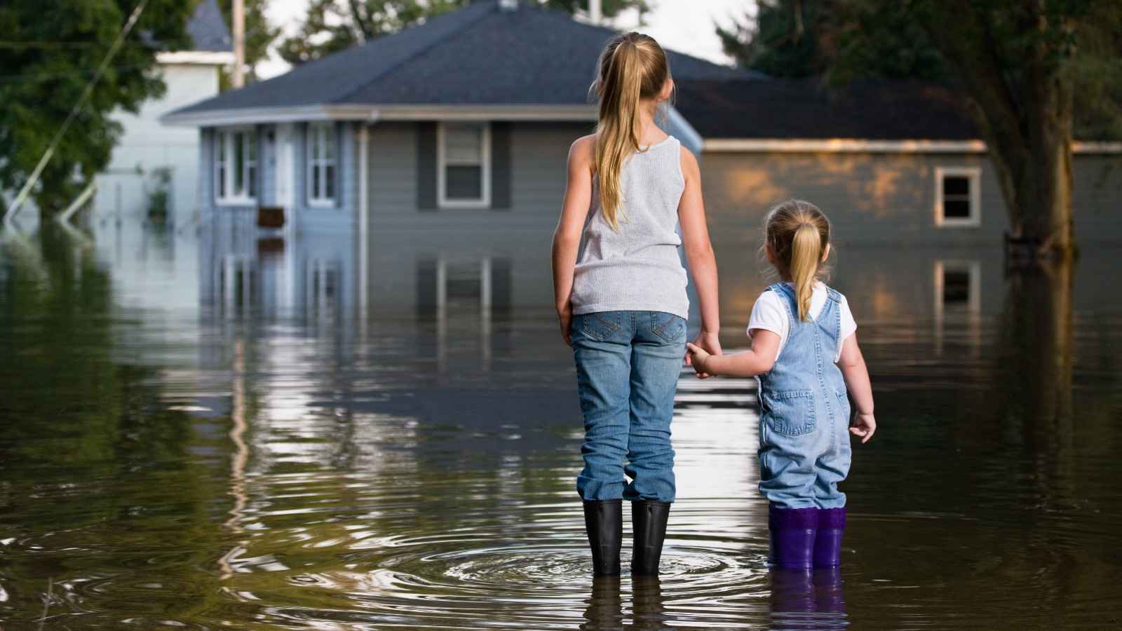 Kinder stehen vor überflutetem Haus