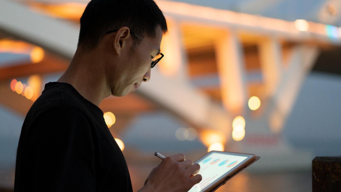 Man with tablet in front of bridge