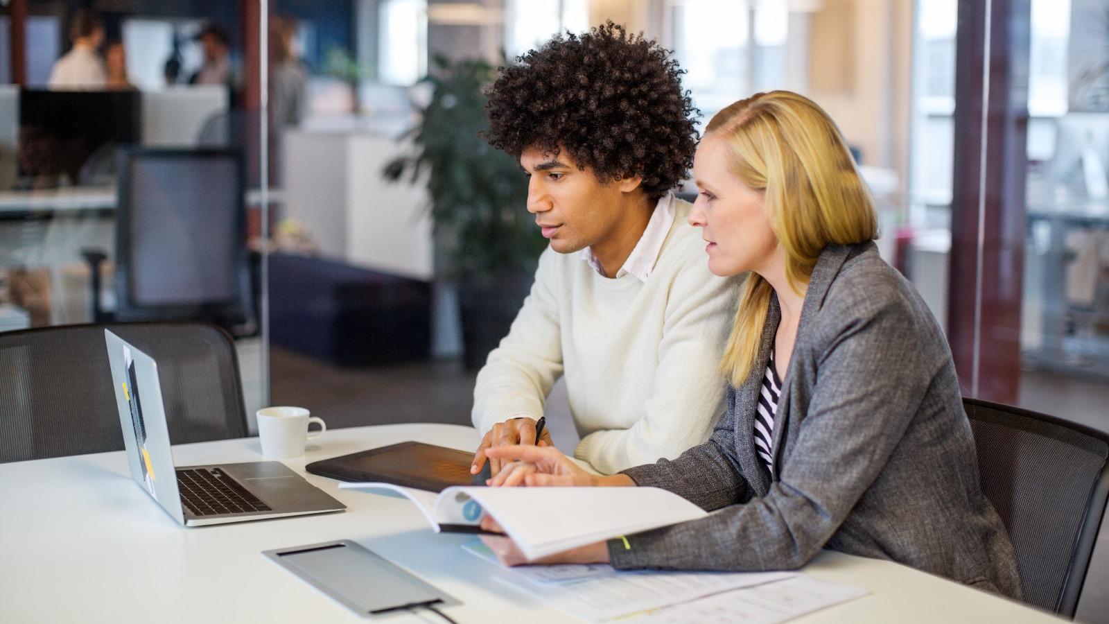 Mann und zwei Frauen schauen auf Laptop