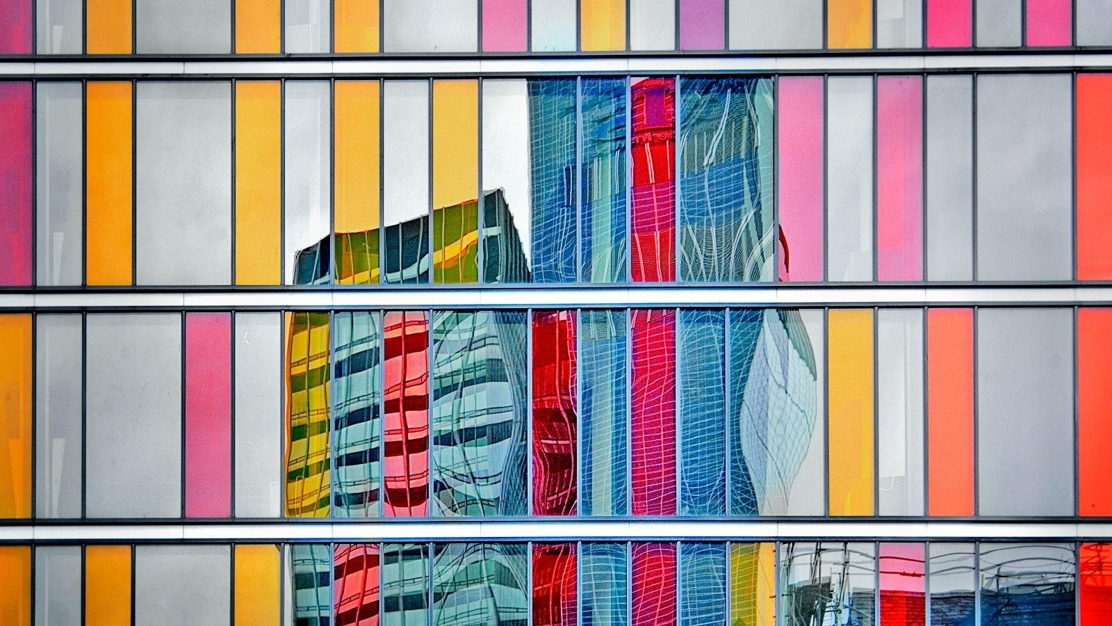 Hochhäuser spiegeln sich in bunter Fassade