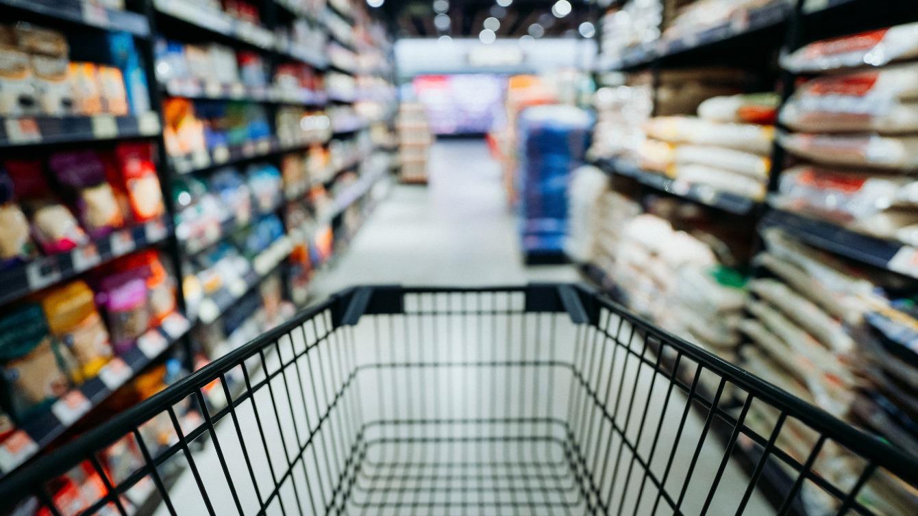 Blick über Einkaufswagen in Supermarktgang