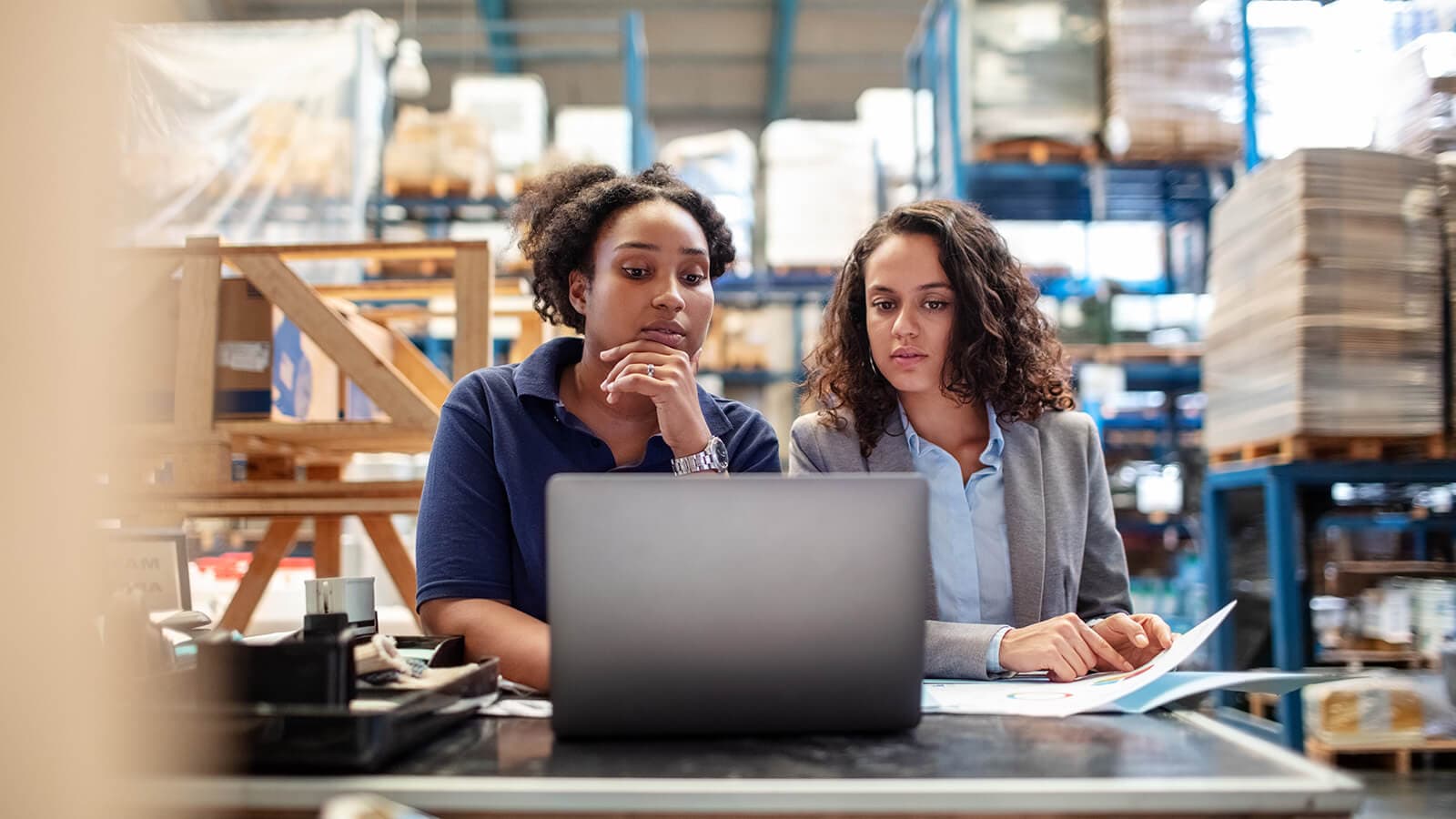Weibliche Arbeiterin mit Betreuerin arbeitet am Laptop
